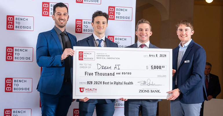 Four men wearing suits hold an oversized cheque