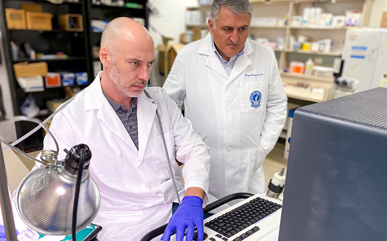 heart-and-blood-vessel-research-01 Two researchers in white coats analyze a lab report on a monitor.