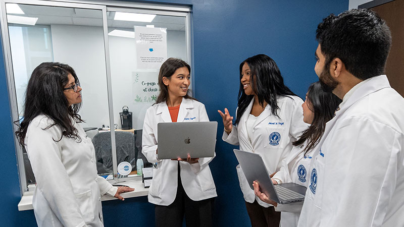 Medical students in white coats compare notes in the NEOMED Free Clinic.