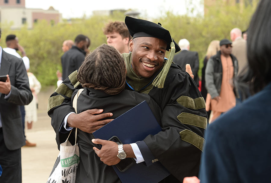 strategic-plan-2025-08 A graduate is hugged by a family member after commencement.